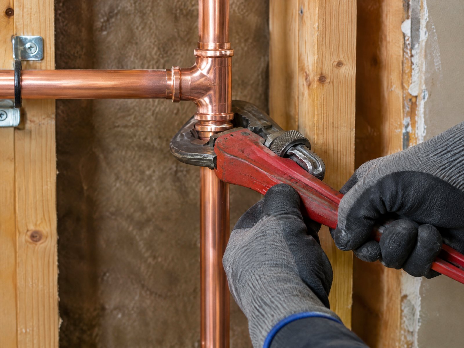 New copper pipes being installed inside an open wall